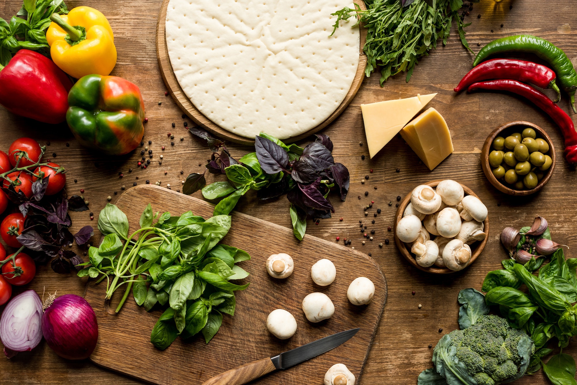 top view of raw pizza dough and fresh ingredients on wooden tabletop